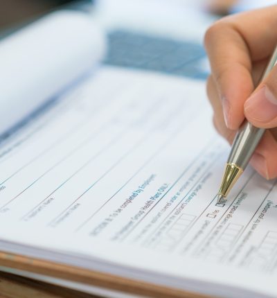 Hand with pen over application form